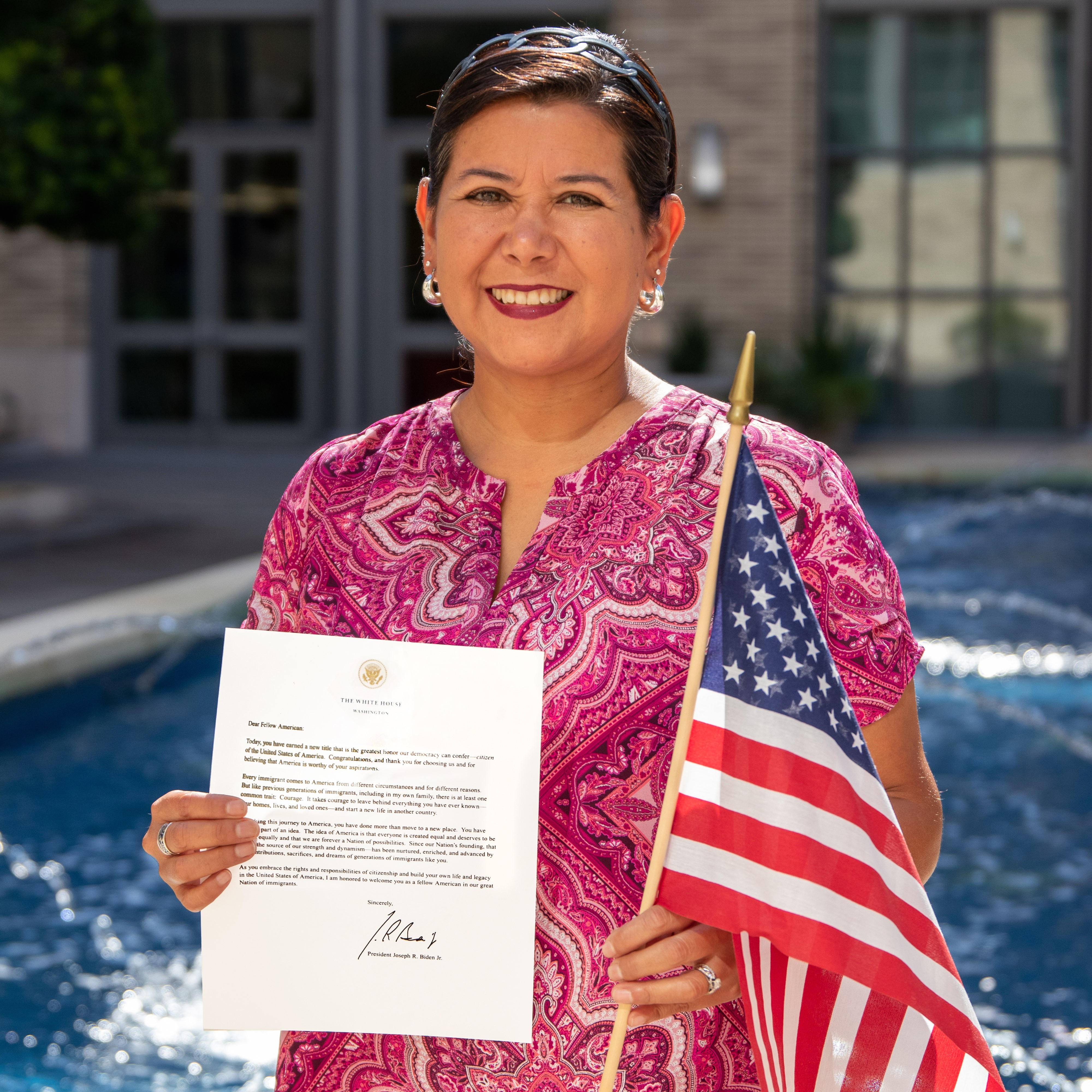 Milu Benko holding an American flag and her letter from the US citizenship and immigration services