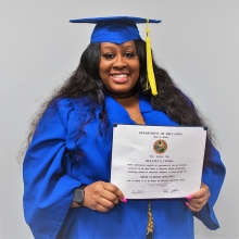 Tiffaney Capers in a cap and gown, holding her diploma